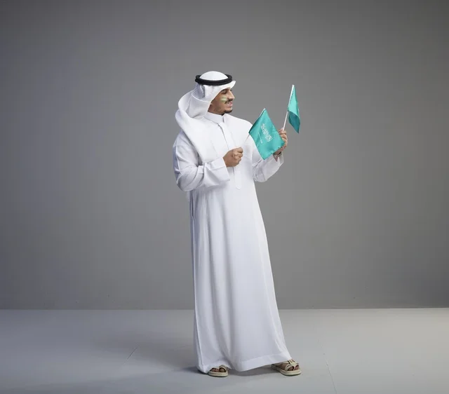 رجل سعودي يحمل الأعلام الوطنية في استوديو