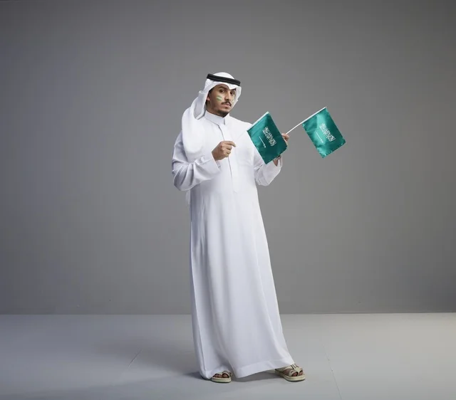 رجل سعودي يحمل الأعلام الوطنية السعودية في الاستوديو