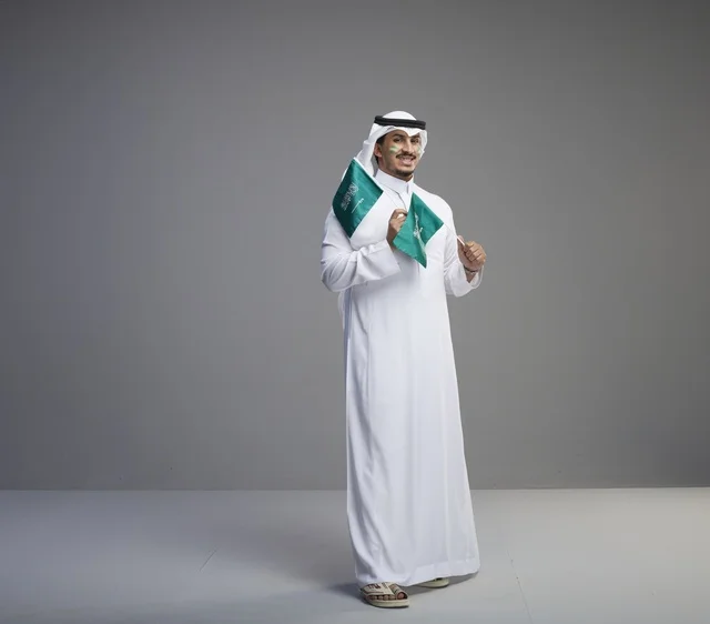 رجل سعودي يحمل الأعلام الوطنية في الاستوديو