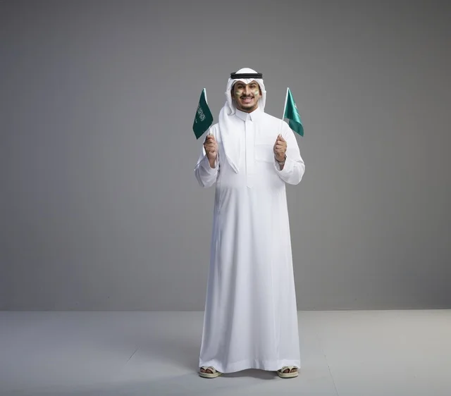 Saudi Man Holding National Flags on Grey Background