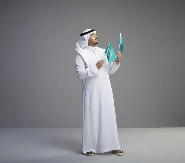 Saudi Man Holding National Flags on Grey Background