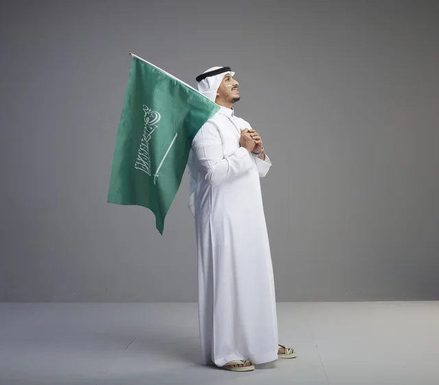 رجل سعودي يحمل العلم الوطني في الاستوديو