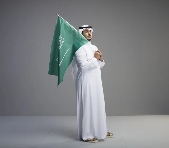 رجل سعودي يحمل العلم الوطني في الاستوديو
