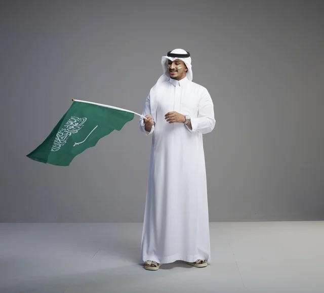 رجل سعودي يحمل علم المملكة العربية السعودية في استوديو