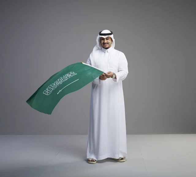 Saudi Man in Traditional Dress Holding National Flag