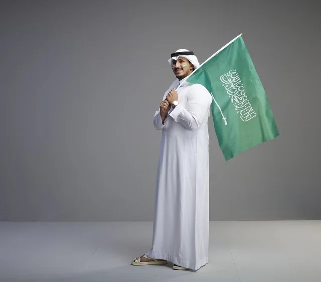 Saudi Man Holding National Flag in Studio Portrait