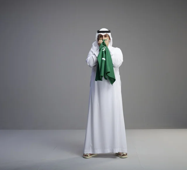 Saudi Man Holding National Flag in Studio Portrait
