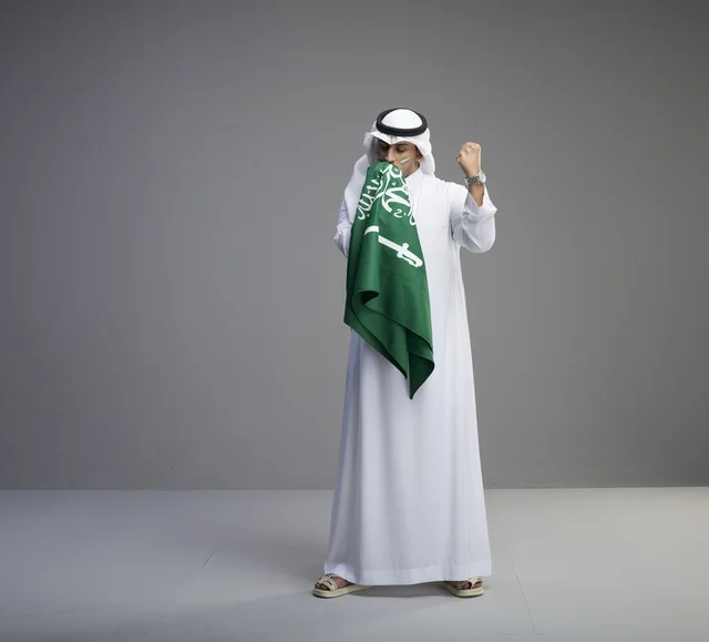 Saudi Man Kissing Saudi Arabia Flag on Grey Background