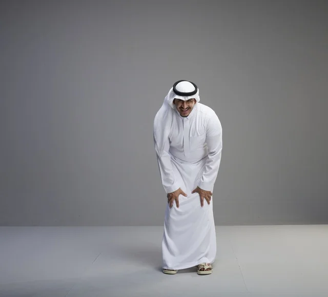 رجل سعودي بالثوب التقليدي يضحك في استوديو