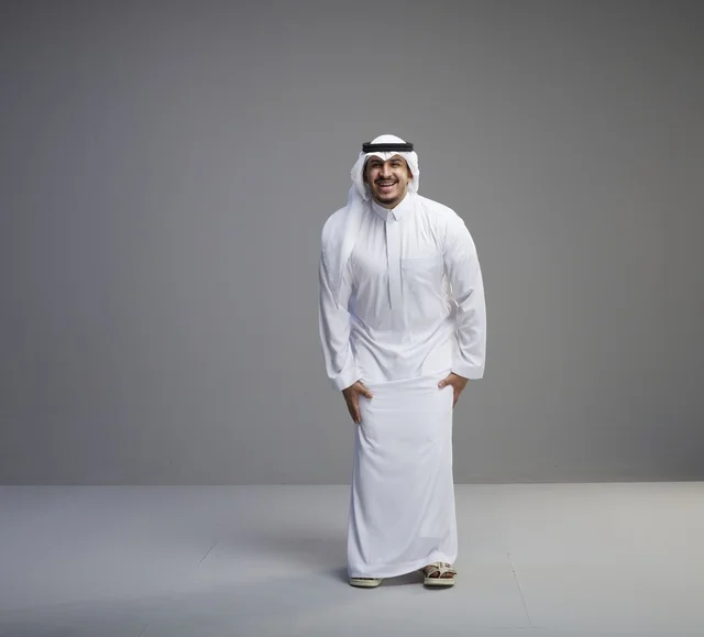 رجل سعودي بالثوب الأبيض التقليدي على خلفية رمادية