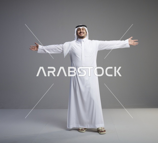 رجل سعودي بالثوب التقليدي يفتح ذراعيه في الاستوديو