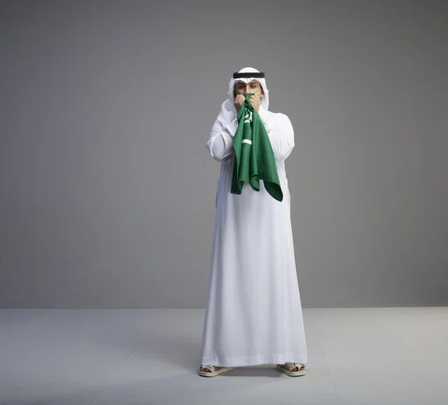 Saudi Man Kissing National Flag in Studio Background