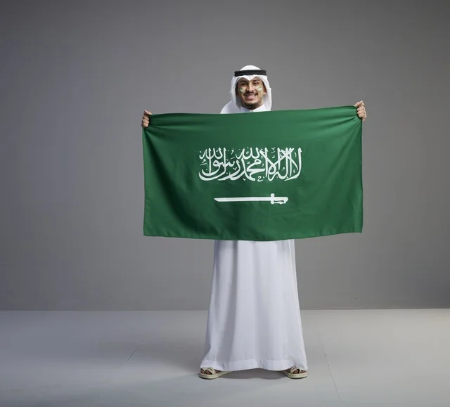 رجل سعودي يحمل العلم الوطني السعودي في الاستوديو