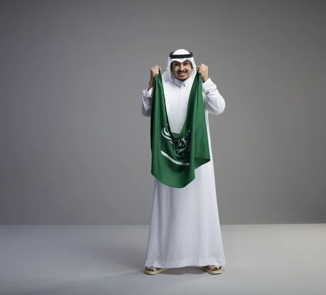 رجل سعودي يحمل العلم الوطني السعودي في الاستوديو