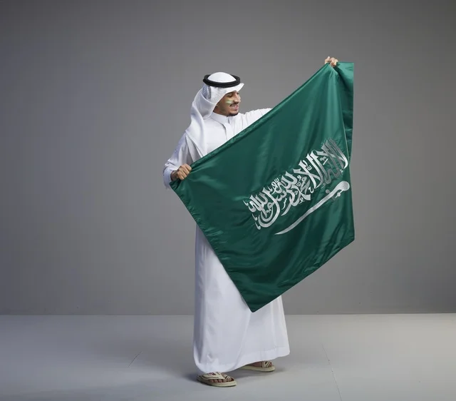 رجل سعودي يحمل العلم الوطني السعودي في استوديو