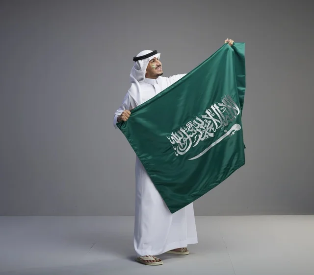 رجل سعودي يحمل العلم الوطني السعودي في الاستوديو