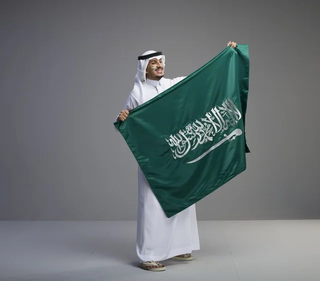 Saudi Man Holding National Flag in Studio Portrait