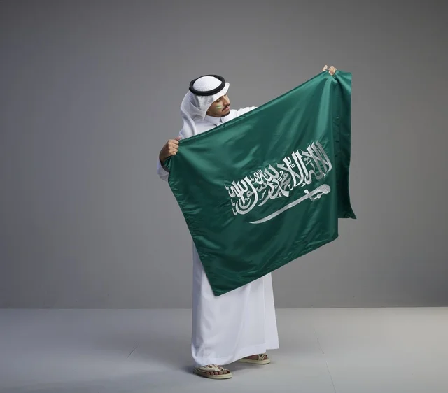Saudi Man Holding National Flag in Studio Setting