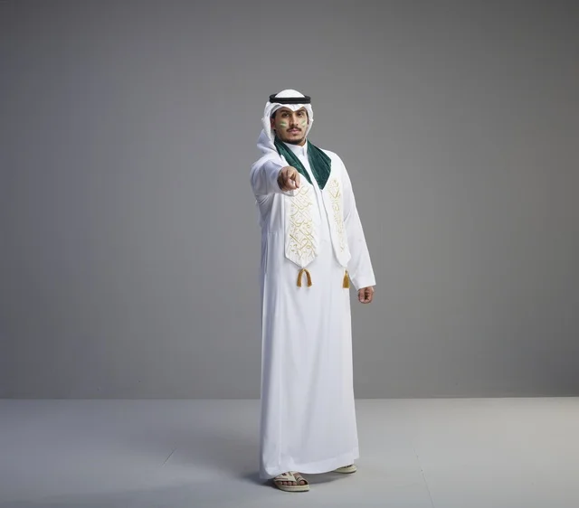 رجل سعودي بالزي التقليدي يشير بيده في الاستوديو