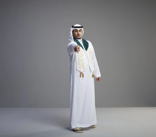 خريج سعودي بالزي التقليدي يشير بإصبعه في الاستوديو