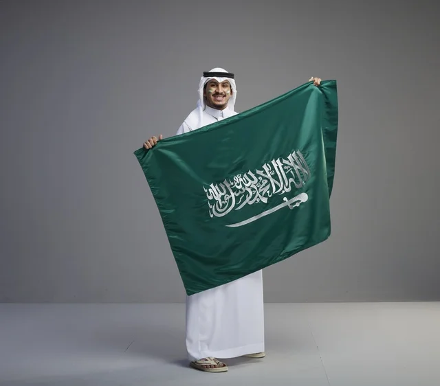 رجل سعودي يحمل علم المملكة العربية السعودية في الاستوديو