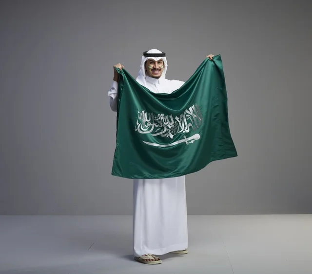 Saudi Man Holding National Flag in Studio Portrait