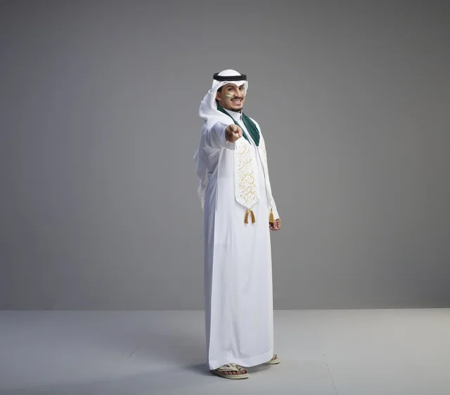 Saudi Male Graduate in Traditional Thobe Pointing at Camera
