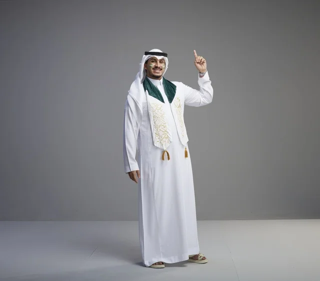 رجل سعودي بالثوب التقليدي يشير للأعلى في الاستوديو