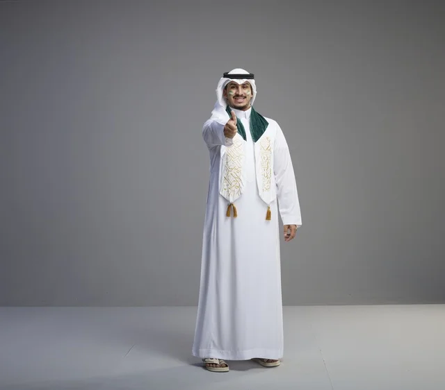 خريج سعودي بالزي التقليدي يشير بعلامة النجاح