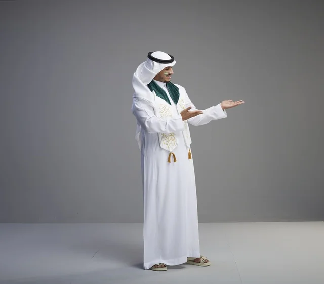 شاب سعودي بالزي التقليدي يشير بيده في استوديو