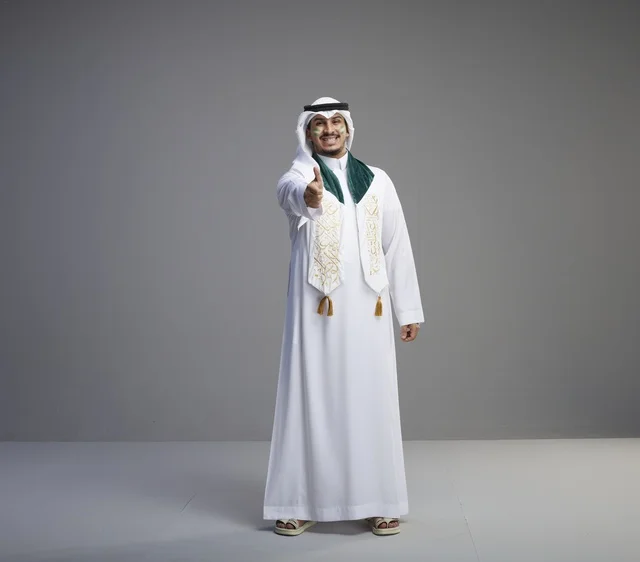 خريج سعودي بالزي التقليدي يشير بعلامة الإعجاب