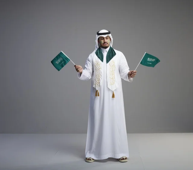 Saudi Man Holding National Flags in Studio Setting