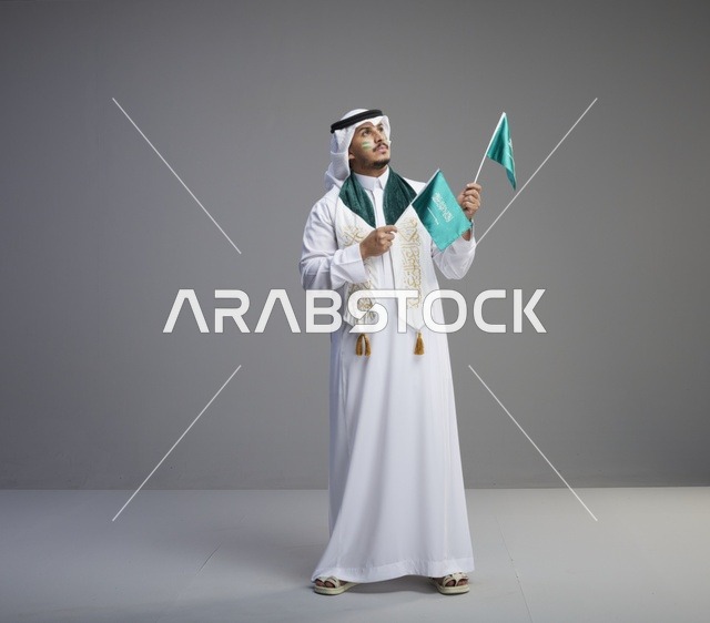 رجل سعودي يحمل الأعلام الوطنية في الاستوديو
