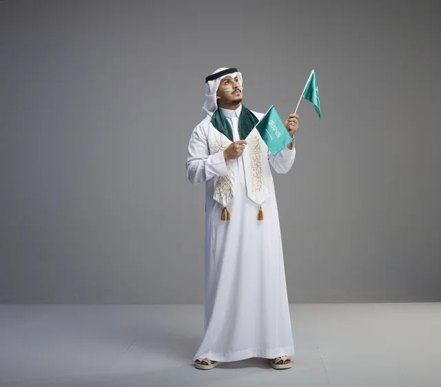 رجل سعودي يحمل الأعلام الوطنية في الاستوديو
