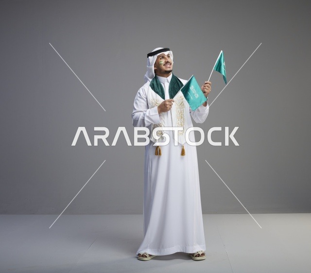 رجل سعودي يحمل الأعلام الوطنية السعودية للاحتفال