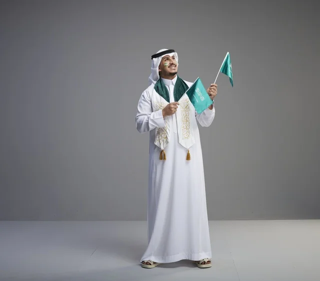 رجل سعودي يحمل الأعلام الوطنية السعودية للاحتفال