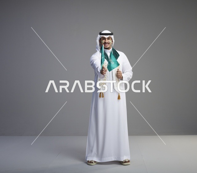رجل سعودي يحمل الأعلام الوطنية في الاستوديو