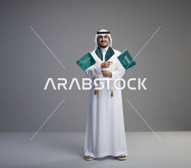 رجل سعودي يحمل الأعلام الوطنية في الاستوديو