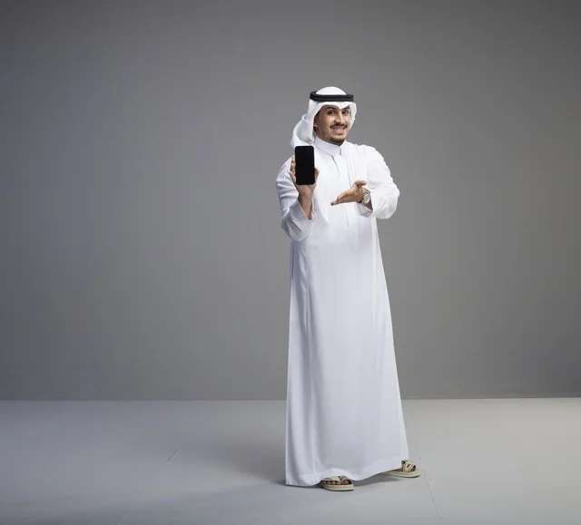 رجل سعودي يحمل هاتف بشاشة فارغة في الاستوديو