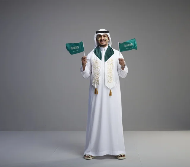 Saudi Man Holding Flags for National Day Celebration
