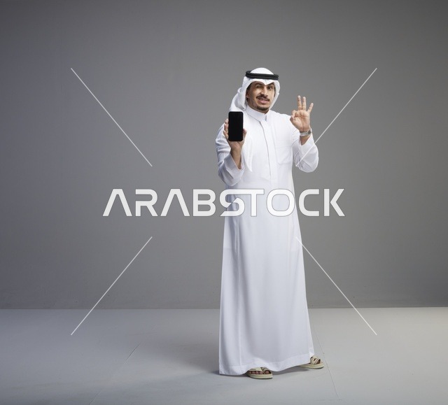 رجل سعودي يحمل هاتف ذكي بشاشة فارغة