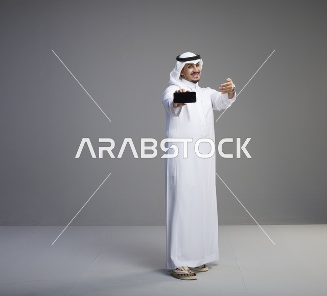 رجل سعودي يحمل هاتف ذكي بشاشة فارغة