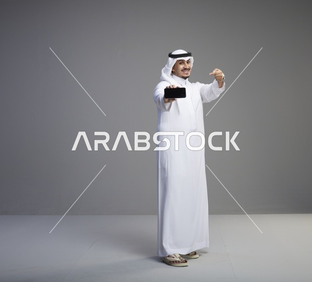 رجل سعودي يحمل هاتف ذكي بشاشة فارغة