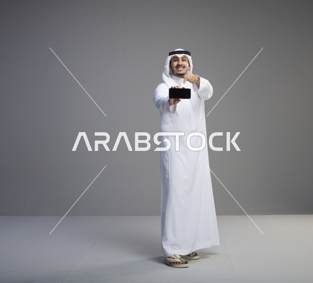 رجل سعودي يشير إلى شاشة هاتف ذكي فارغة