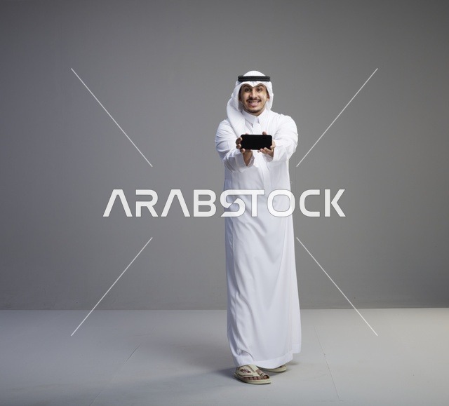 رجل سعودي يحمل هاتف ذكي بشاشة فارغة