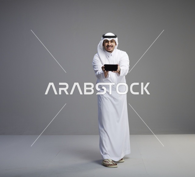 رجل سعودي يمسك هاتف ذكي بشاشة فارغة