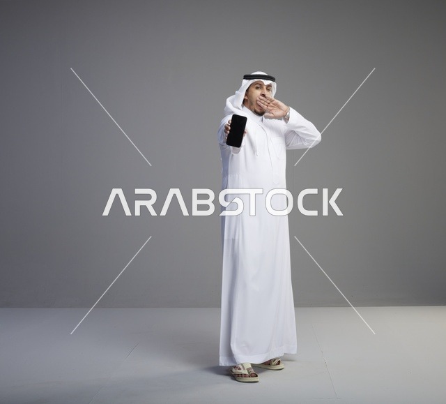 رجل سعودي يحمل هاتف ذكي بشاشة فارغة وينادي