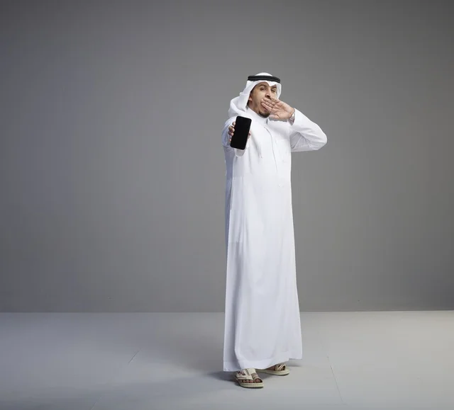 رجل سعودي يحمل هاتف ذكي بشاشة فارغة وينادي