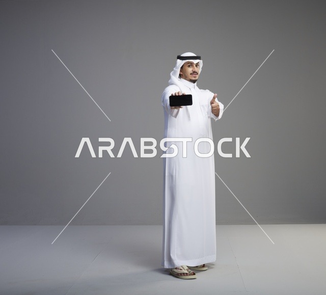 رجل سعودي يحمل هاتف ذكي بشاشة فارغة