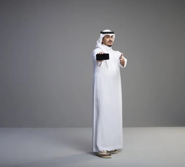 رجل سعودي يحمل هاتف ذكي بشاشة فارغة